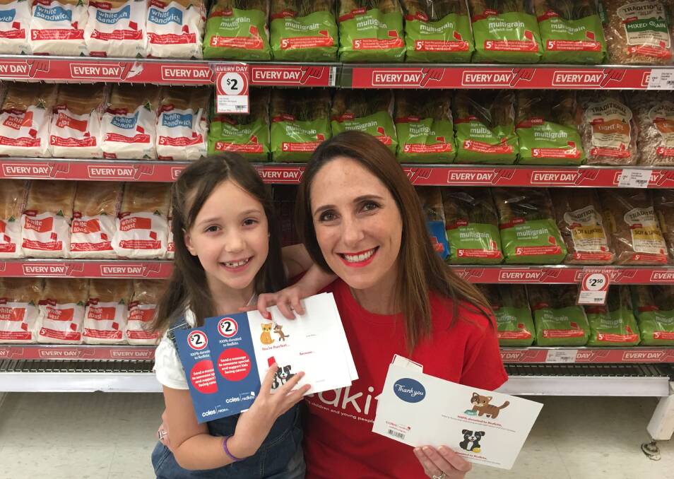 Kindness: Redkite manager Monique Keighery and her daughter Izzara holding the new donation cards available at Coles. Photo: Supplied.