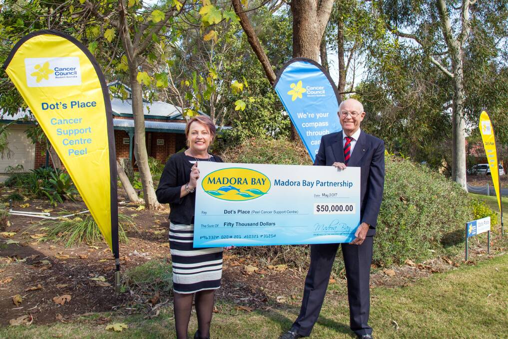Philanthropic boost: John Perry hands the cheque on behalf of the Madora Bay Partnership to Cancer Council WA support services director Sandy McKiernan. Photo: Linda Smith.