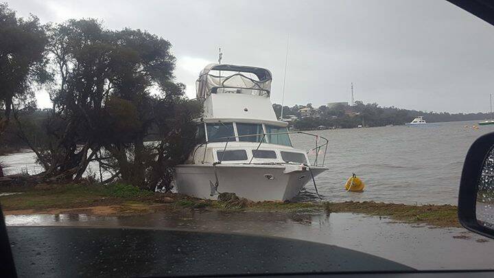 Land ho: a boat has been ripped from its moorring and banked against rocks in Dawesville. Photo: Facebook/Renee Robbins.
