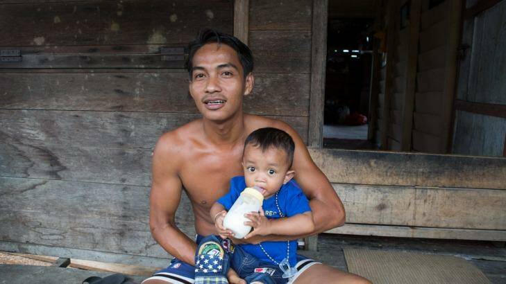 Tengku Antonia bottle feeds his son Tengku Ayuan Kuadi outside his home in Pelalawan village, in Riau province. Photo: Rodrigo Ordonez