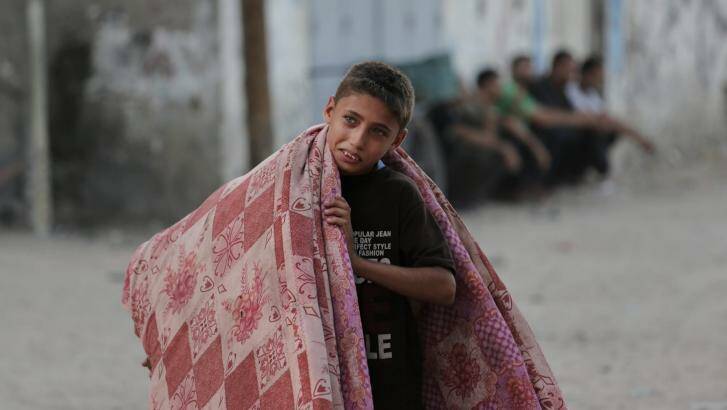 A Palestinian boy carries mattresses as he flees the family house. Photo: AP Photo/Lefteris Pitarakis