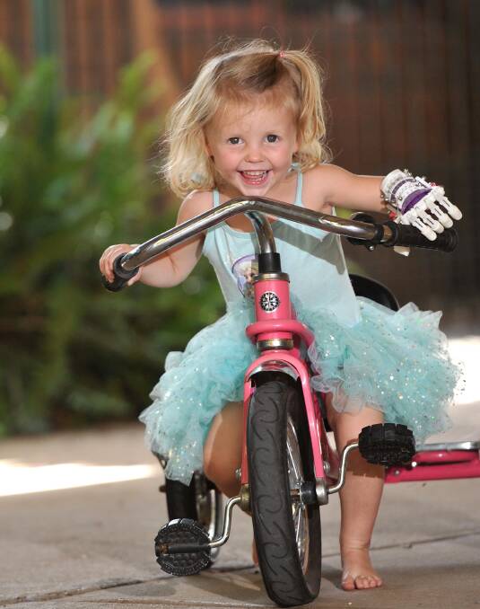 RIDING AHEAD: Libby Evans, 2, rides a bike with both hands for the first time in her life thanks to a robotic hand made from a 3D printer in Wagga. Picture: Laura Hardwick
