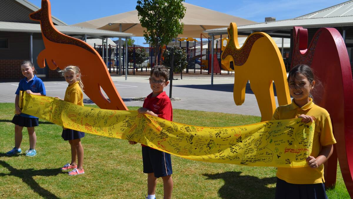 Meadow Springs Primary School year two/three students Lillian Nie, Jessica McVicker, Riley Nixon Batavia Moore with a small section of the ribbon.