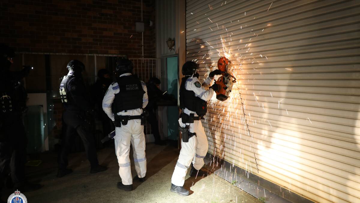 Raptor Squad officers cutting through a roller door at the Mongol clubhouse. Picture via NSW Police