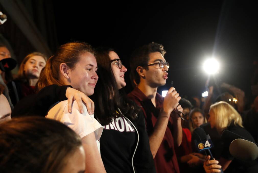 Diego Pfeiffer, a student survivor from Marjory Stoneman Douglas High School, speaks to a crowd of supporters and media, while fellow survivors Sophie Whitney, left, and Sarah Chadwick embrace after they arrived at Leon High School, in Tallahassee, Florida. Photo: AP Photo/Gerald Herbert.