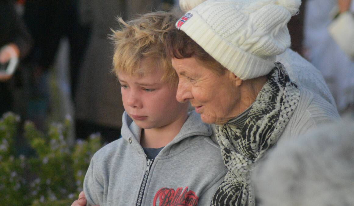 A boy cries as he and a woman look at the wreaths. 