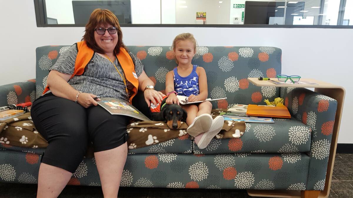 Volunteer Stephanie White and Flynn the story dog help reluctant or struggling readers to build confidence in reading out loud. Photo: Supplied.