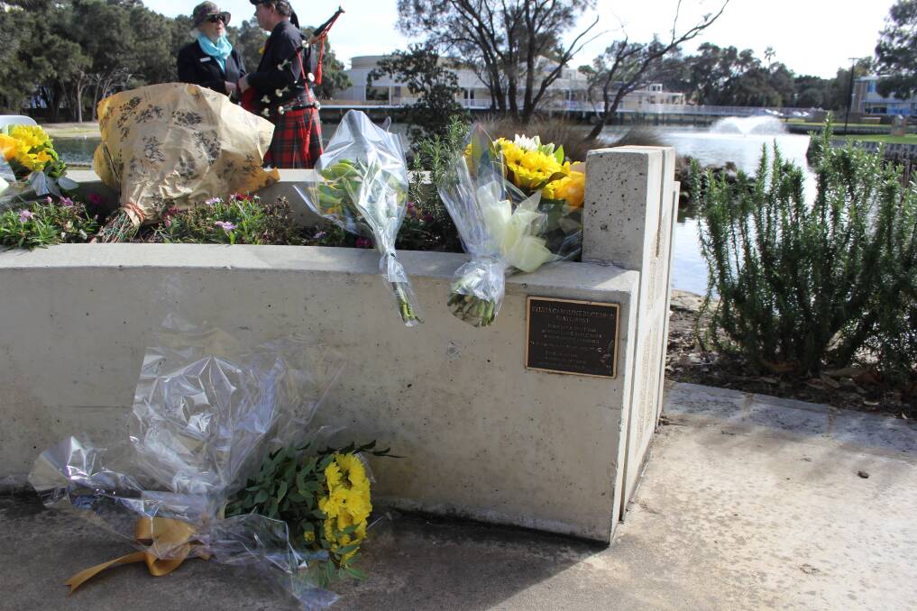 Attendees laid flowers at the memorial as bag pipes played in the background. Photo: Claire Sadler.