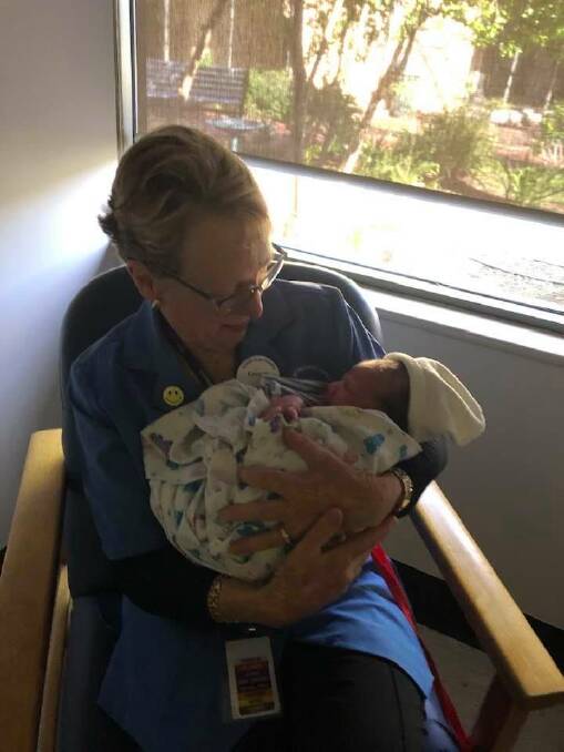 Loretta cuddles a newborn while volunteering at Peel Health Campus.