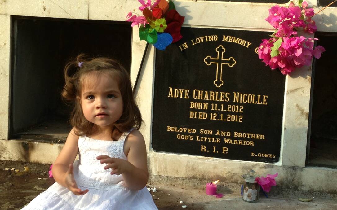 Lilah Nicolle pictured sitting next to the memorial for her brother, Adye. Photo: Supplied.