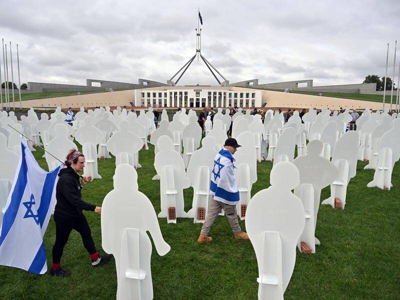 Israeli protesters walk past cutout effigies, representing hostages, during a protest in Canberra. (Mick Tsikas/AAP PHOTOS)