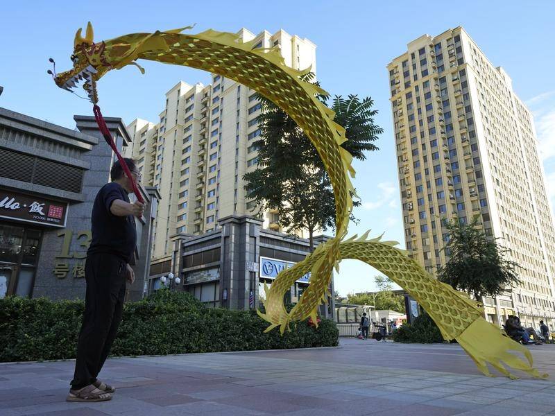 A resident wields a cloth dragon outside the Evergrande Yujing Bay residential complex in Beijing.