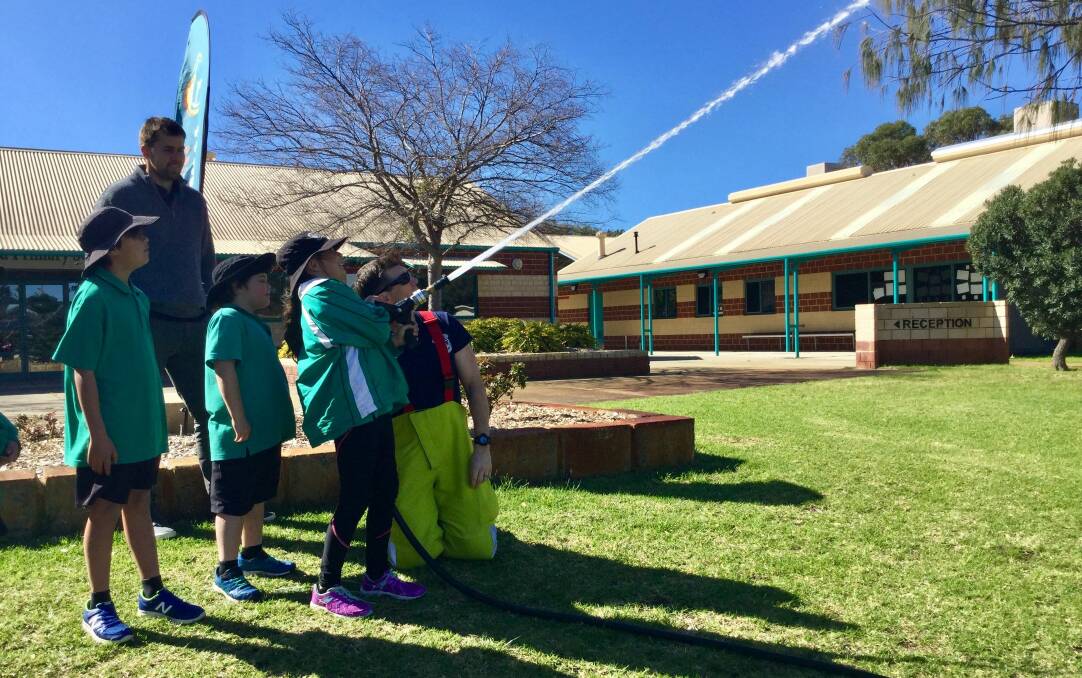 Safety first: Some Halls Head Primary School Year 3 students having a go with a fire hose at the recent Fire Safety visit. Photo: Supplied.